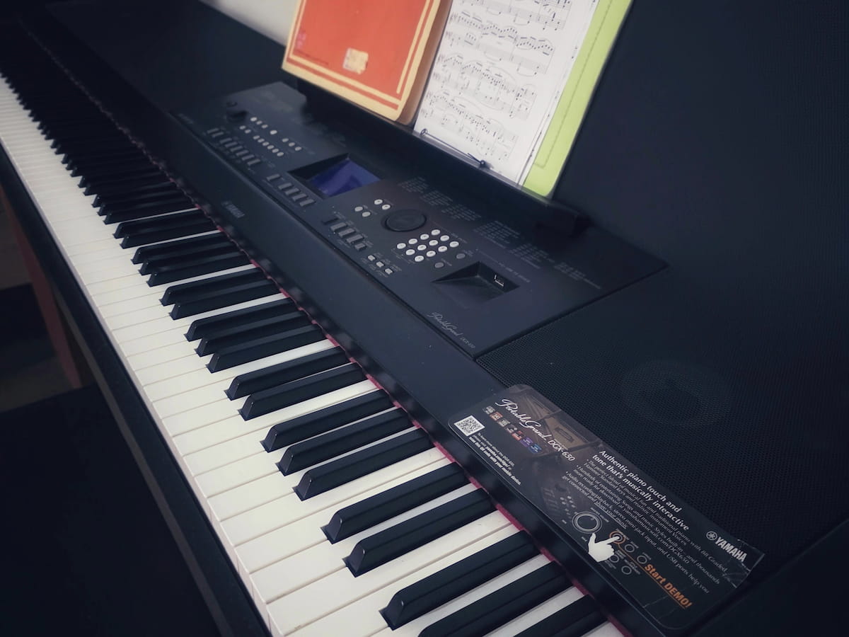 Pianoforte digitale Yamaha DGX-650 e alcuni libri di studio leggermente visibili su leggio