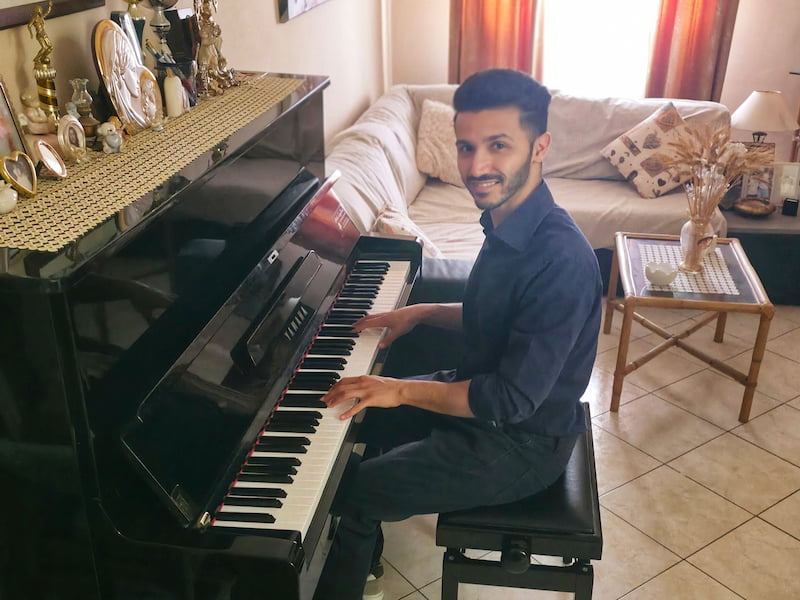 Omar al pianoforte in salotto curato che sorride